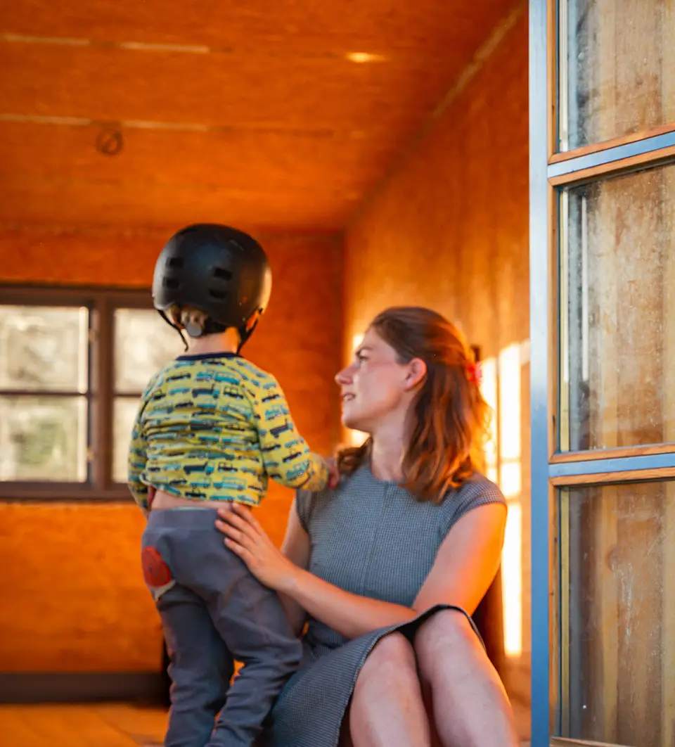 Kind mit Fahrradhelm und Erwachsene im Bauwagen am Lernort Groß Volksitz auf Rügen – Geborgenheit, Naturpädagogik und Urlaub mit Kindern.